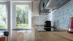 Una cocina moderna con ventanal, radiador y un electrodoméstico rojo.