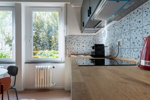 A modern kitchen with a window, a radiator, and a red appliance. - Porta21 Studio [Linate, Osp.Monzino, Arena Santa Giulia] (Milano)