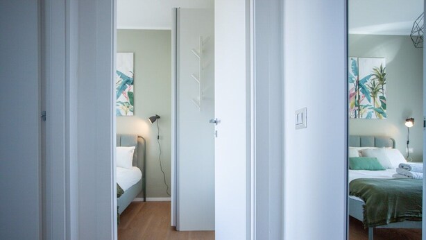 Habitación de hotel con cama, mesita de noche, lámpara y una obra de arte en la pared.