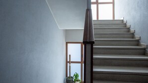 Una escalera con barandilla de madera que lleva a una plataforma con una puerta y una ventana.