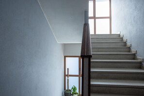 A staircase with a wooden handrail leading to a landing with a door and a window. - Porta21 Studio [Linate, Osp.Monzino, Arena Santa Giulia] (Milano)