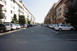 A street lined with parked cars and multi-story residential buildings.
