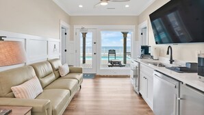 A modern kitchen with a large TV, a dining area with a view of the ocean, and a cozy seating area with a leather sofa. - Experience oceanfront bliss at Magic Hour, Oak Island's spacious 7-bedroom retreat for 16. (Oak Island)
