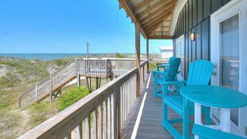 A wooden deck with a view of the beach and ocean.