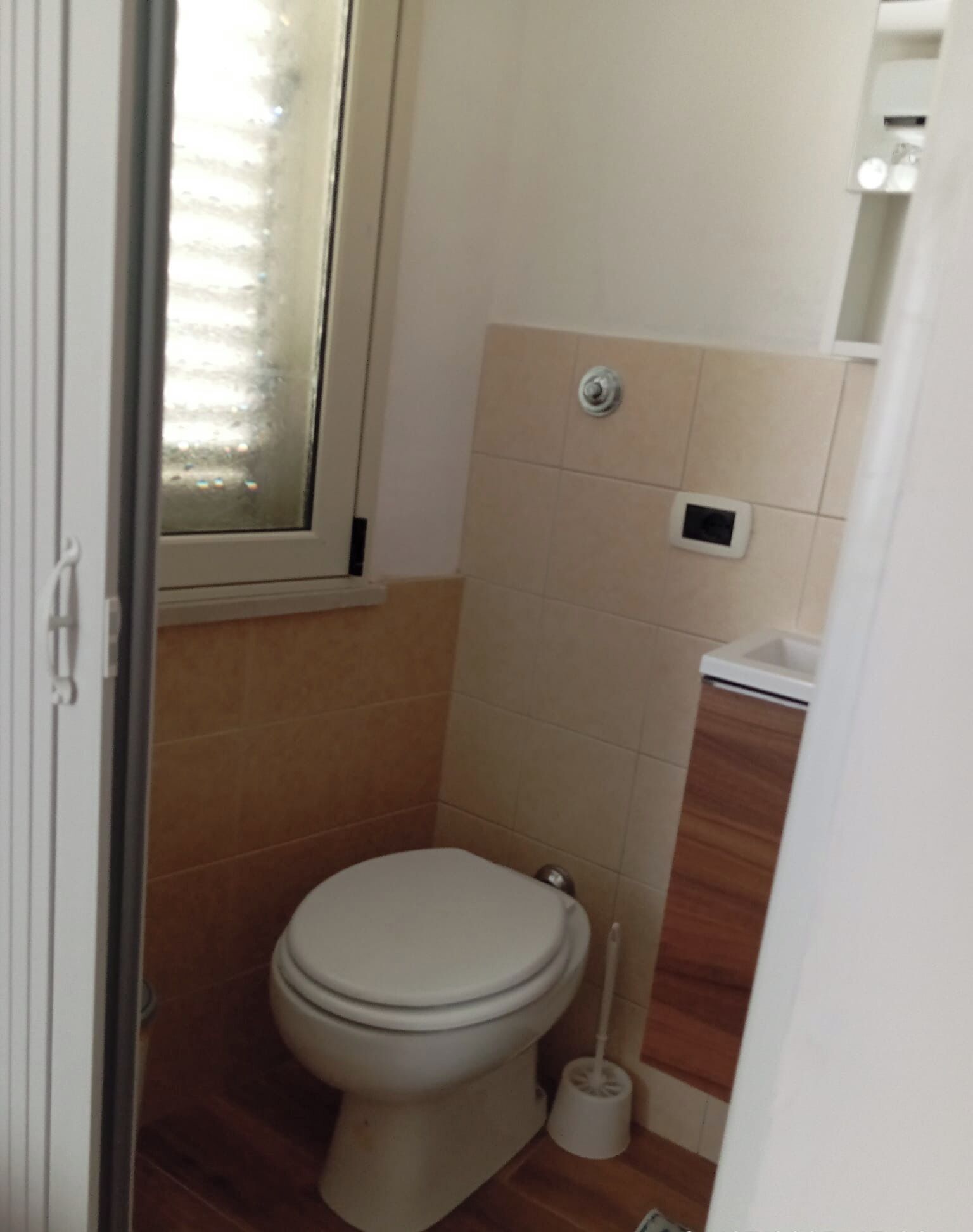 A small, compact bathroom with a toilet, a bidet, and a window.