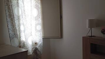 Une chambre avec un lit, une table de chevet, une lampe et un climatiseur fixé au mur.