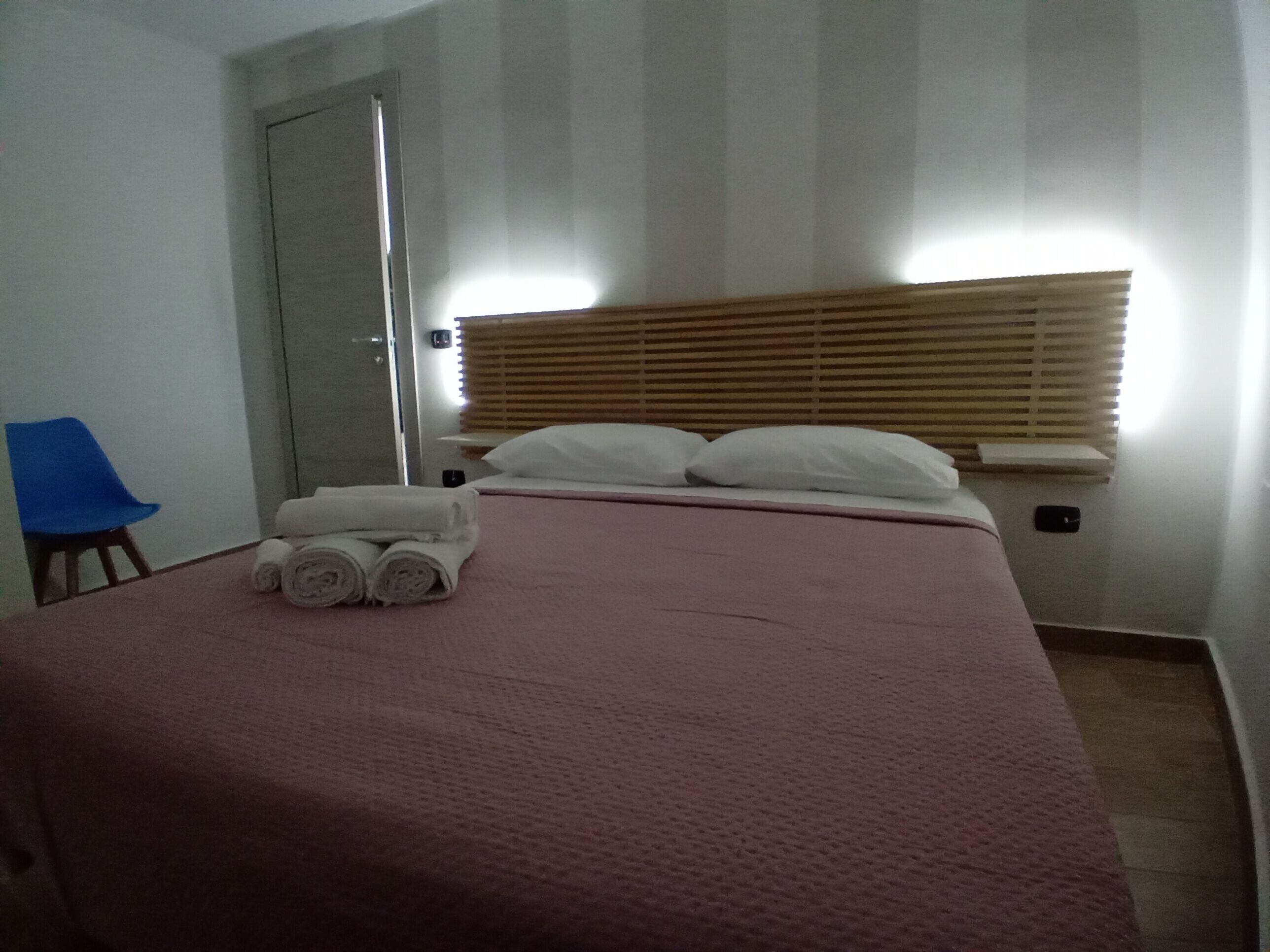 Habitación de hotel con cama, una silla, una puerta y una ventana con persianas.