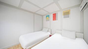 A modern hotel room with two single beds, a wooden floor, and a large window.