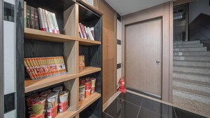 A modern interior with built-in bookshelves and storage units, a fire extinguisher, and a staircase. - HUE MOTEL (Gumi)