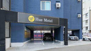 The exterior of the Hue Motel with a covered parking area and a black car parked inside. - HUE MOTEL (Gumi)