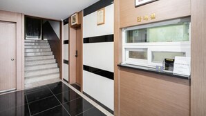 A reception area with a reception desk, a staircase, and a framed certificate on the wall. - HUE MOTEL (Gumi)