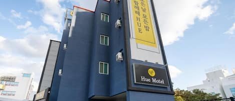 A modern building with a blue facade and a sign for Hue Motel.