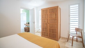 Ein Schlafzimmer mit einem Bett, einem Holzschrank, einem Stuhl und einem Schreibtisch mit Sitzgelegenheit.
