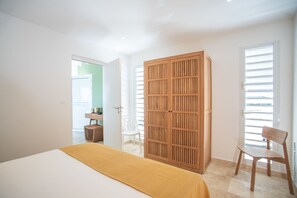 Ein Schlafzimmer mit einem Bett, einem Holzschrank, einem Stuhl und einem Schreibtisch mit Sitzgelegenheit.