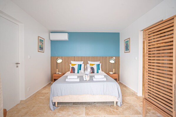 Ein Schlafzimmer mit einem Bett, zwei Nachttischen, einem Holz-Kopfteil, einer Klimaanlage und einem Schrank aus Holz.