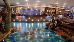 En indendørs pool med et pirattema, inklusive en skeletfigur og et skibsvrag.