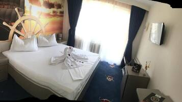 Ein Hotelzimmer mit einem Bett, einem Schreibtisch, einem Stuhl, einem Fernseher und einem Fenster mit Vorhängen.