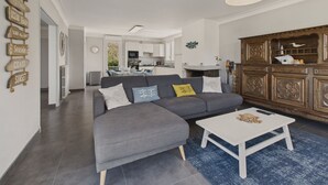 A modern living room with a grey sectional sofa, a white coffee table, and a wooden cabinet with decorative items.