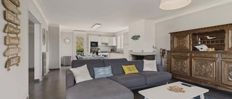 Ein modernes Wohnzimmer mit einem grauen Ecksofa, einem weißen Couchtisch und einer Holzkabine mit Dekorationen.