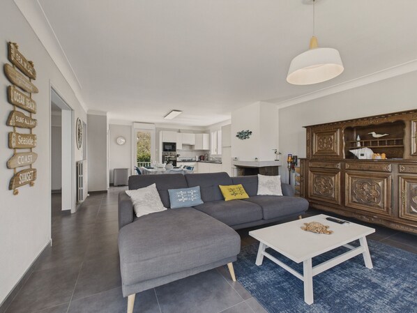 A modern living room with a grey sectional sofa, a white coffee table, and a wooden cabinet with decorative items.