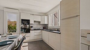 A modern kitchen with white cabinets, a black countertop, and a dining area with a table set for two.