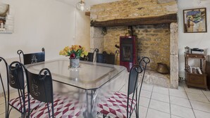 A dining area with a glass table, black chairs, and a stone fireplace.