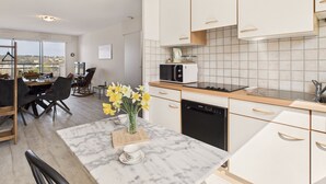 A modern kitchen with white cabinets, a marble countertop, and a view of the city. - Sea view in the city center - Apartment for 6 (Erquy)