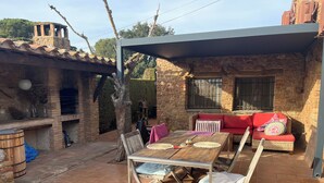 Un patio con un muro de piedra, una mesa de madera y un sofá rojo.