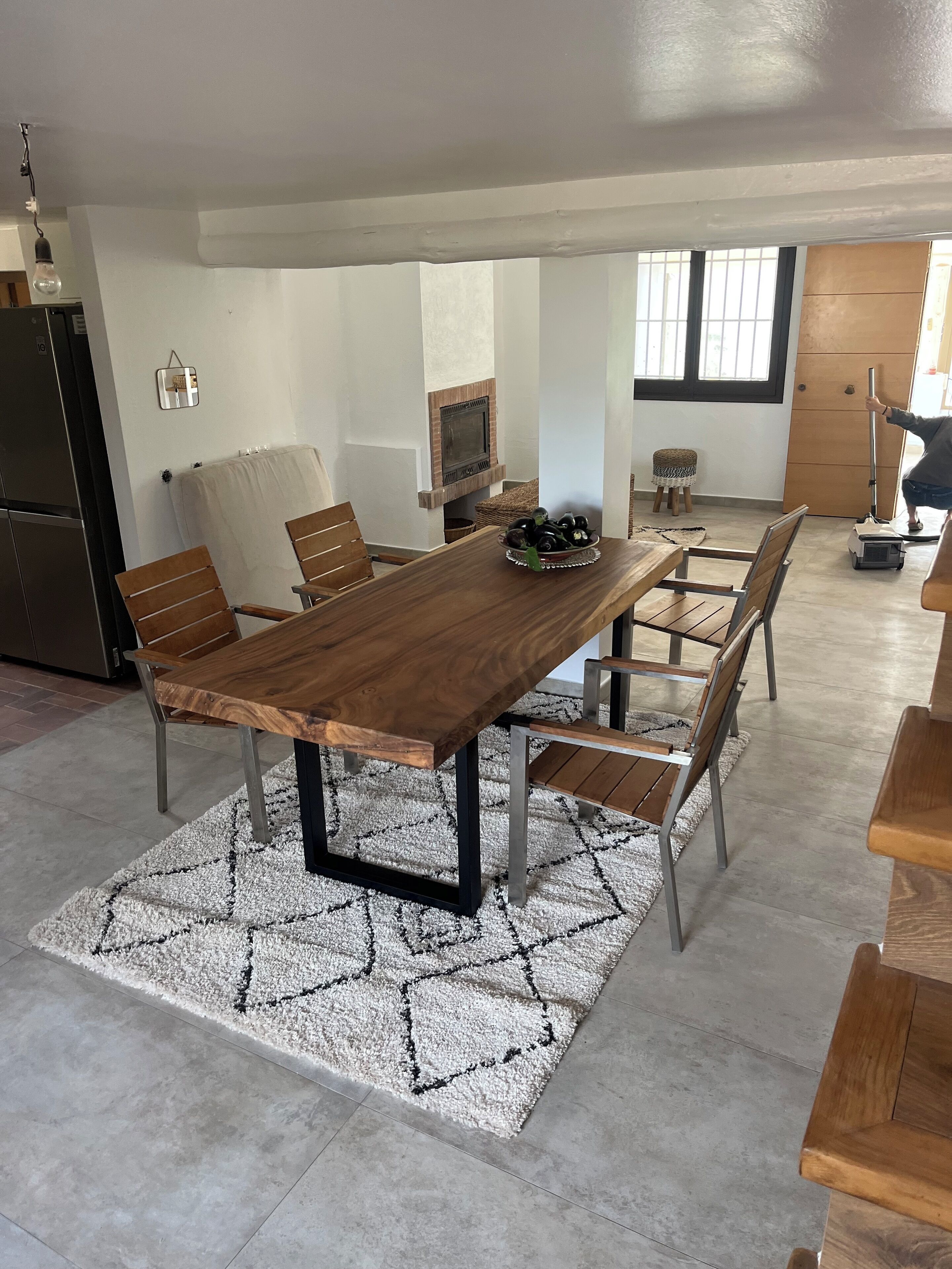 A modern kitchen with a wooden dining table, chairs, and a built-in oven.