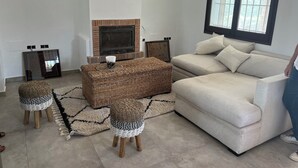 Una sala de estar con un sofá color crema, una chimenea, un ventanal grande y un tapete decorativo.