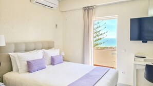 Una habitación de hotel con una cama, televisión, escritorio y vista al mar.