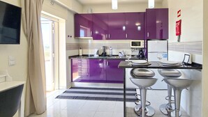 Una cocina moderna con gabinetes morados, un televisor de pantalla plana, un microondas y una cafetera.