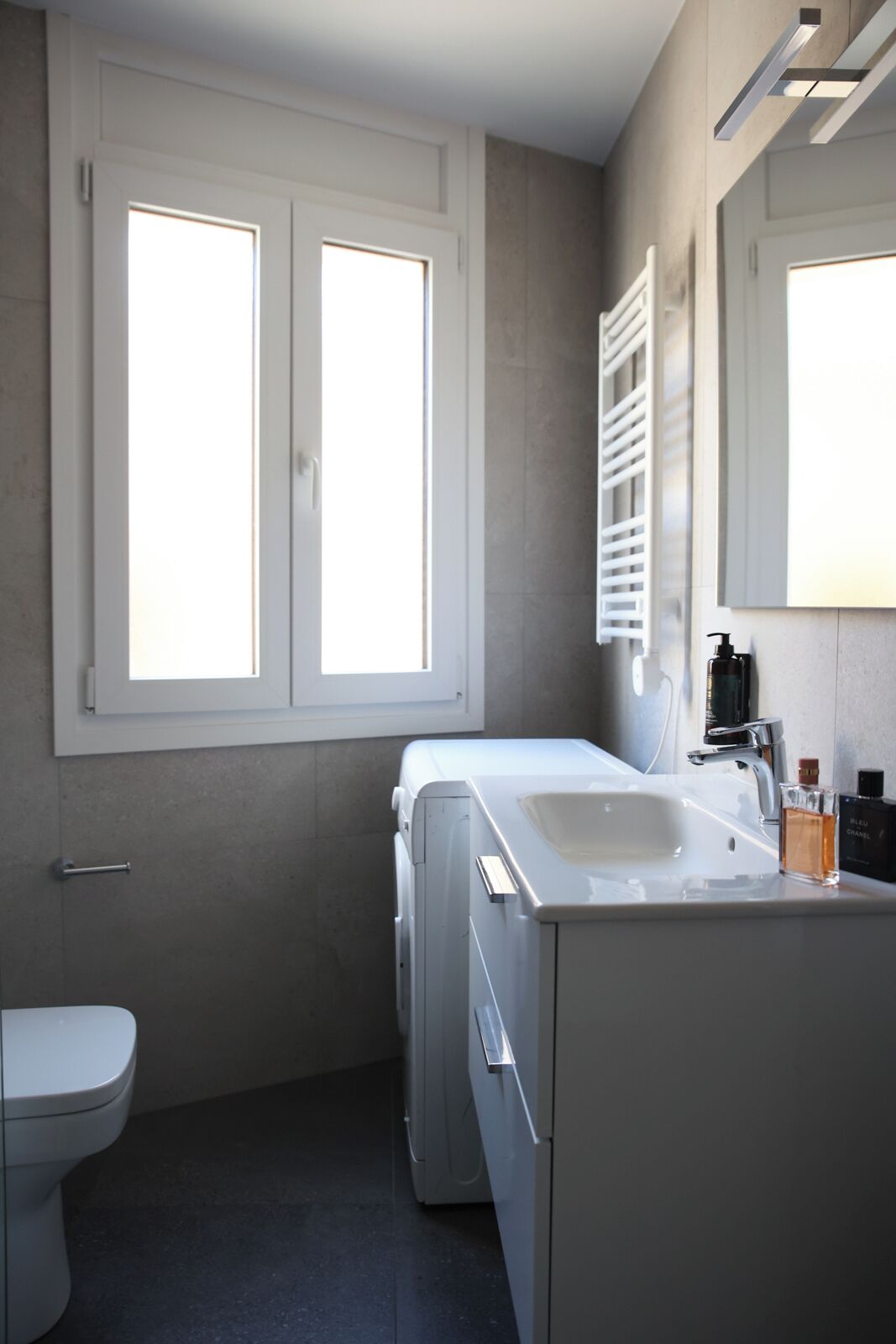 Un baño moderno con inodoro, lavamanos y espejo.
