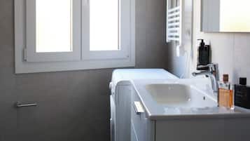Un baño moderno con inodoro, lavamanos y espejo.
