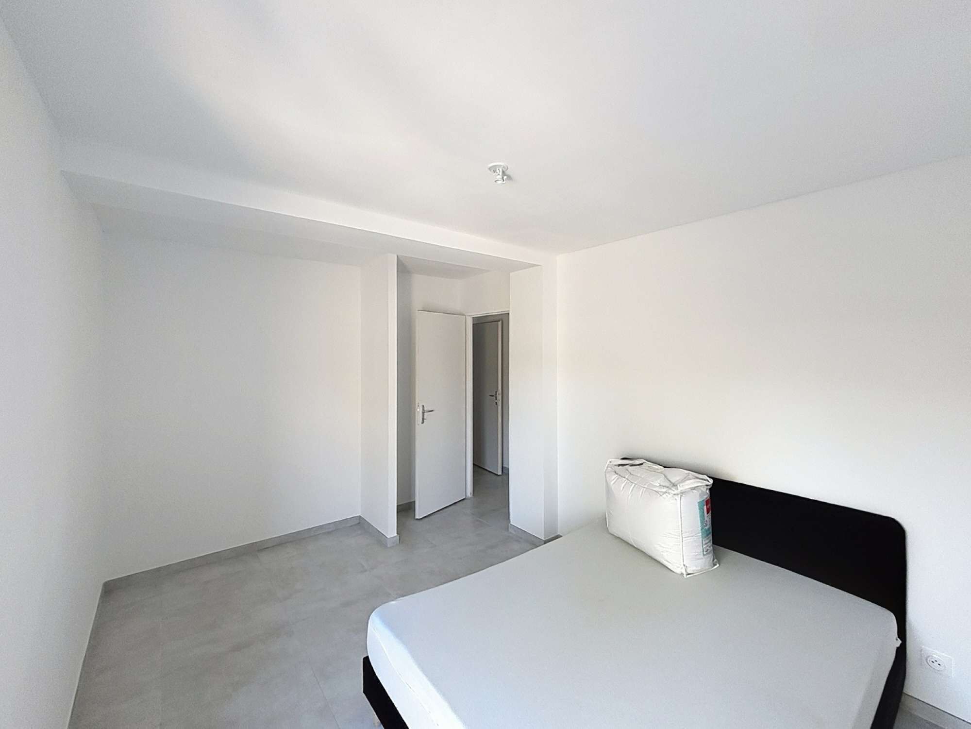 A bedroom with a bed, a door, and a hallway.