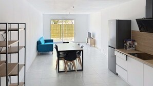 Eine moderne Küche mit Essbereich, einem blauen Sofa und einem großen Fenster.