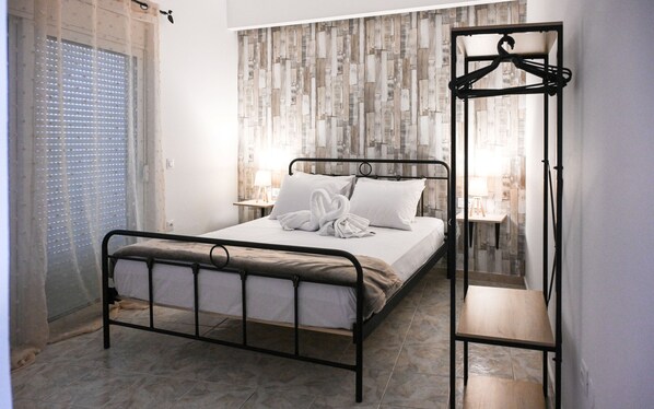 A neatly made bed with a heart-shaped towel, a bedside table with a lamp, and a wall with a wooden plank pattern. - Casa 30 House Complex Center of Ialysos (Rhodes)