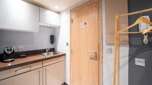 A compact kitchen with a coffee machine, a sink, and a wooden door with a sign. - Urban Getaway: Maillol Suite in the Center with Free Wifi (Perpignan)