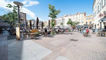 Ett offentligt torg utomhus med sittplatser, en central fontän och omgivande byggnader.