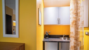 Een kleine keuken met een spoelbak, een koffiezetapparaat en een kastje.