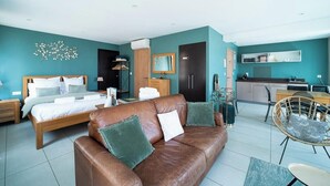 A modern hotel room with a bed, a brown leather sofa, a dining area, and a kitchenette. - Suite Majorca Downtown Free WiFi (Perpignan)