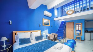 Habitación de hotel con una cama grande, un escritorio, una silla, un balcón y una zona de cocina.