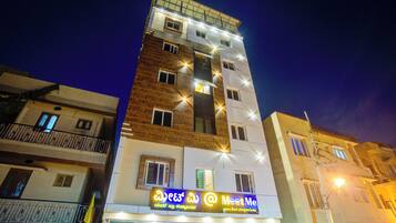 A multi-story building with a 'Meet Me' sign, balconies, and a wooden facade.
