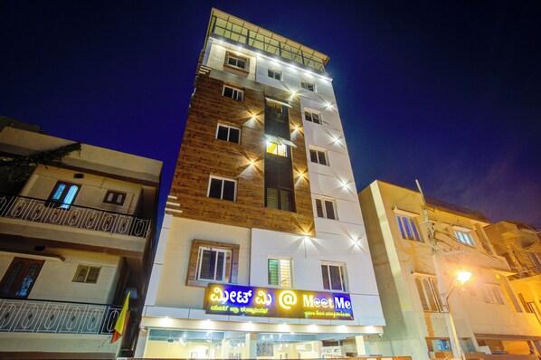 A multi-story building with a 'Meet Me' sign, balconies, and a wooden facade.