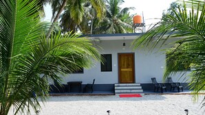 Una casa moderna con una porta in legno, due finestre e un piccolo portico con sedie.