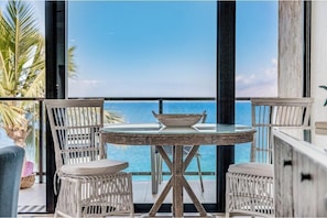 Ein Balkon mit Tisch und Stühlen, mit Blick auf ein Gewässer.