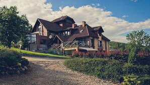 A large, two-story house with a sloped roof, a balcony, and a stone pathway leading to the entrance. - Rezydencja nad Wodospadem Spa&Wellness (Jelenia Gora)