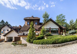 A two-story house with a stone driveway, a small garden, and a bicycle parked outside. - Rezydencja nad Wodospadem Spa&Wellness (Jelenia Gora)