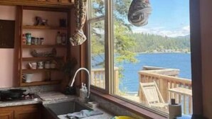 Une cuisine dotée de meubles en bois, d’un plan de travail en granit et offrant une vue sur un lac grâce à une grande fenêtre.