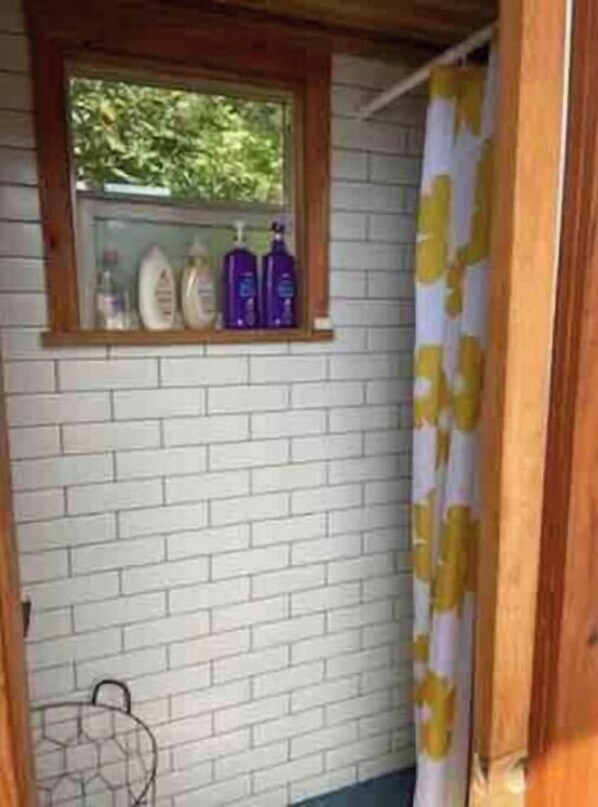 Un baño con ventana, cortina de ducha y artículos de aseo en la pared.